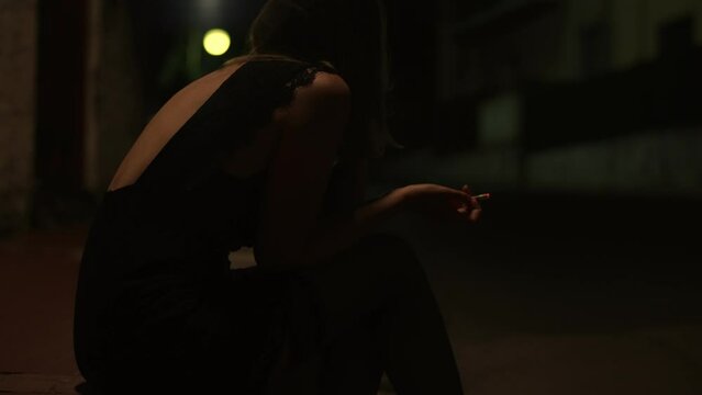 Drunk woman sitting on the night street.
