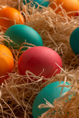 Colorful easter eggs on hay. Bright and colorful eggs on wooden background