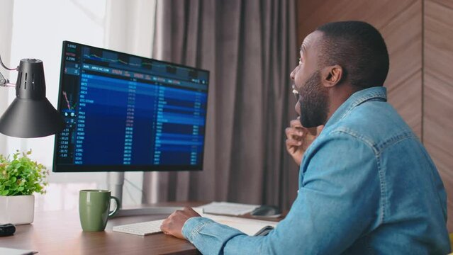 Back side view close up portrait of african american trader looking at stock diagrams on sceen and making super happy expresion, smiling and celebrating. Crypto currency trader. Graphs analysis, stock