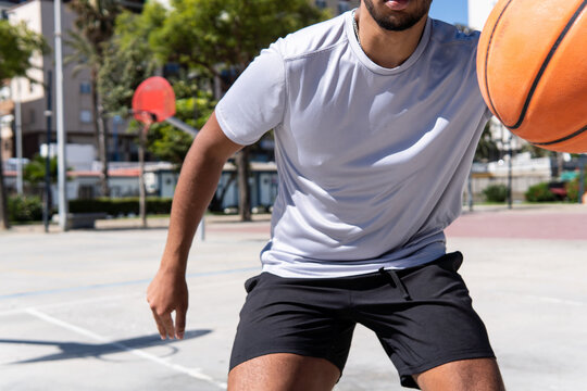 Close up view of an unrecognizable young muslim man playing basketball in the street, city life and training and sport concept