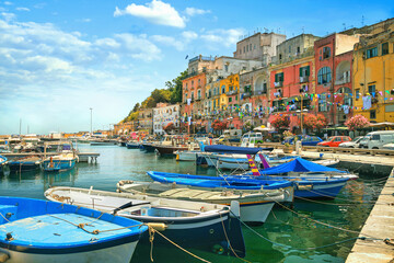 Fototapeta na wymiar Main street with colorful houses and marina with fishing boats in Procida old town. Italy