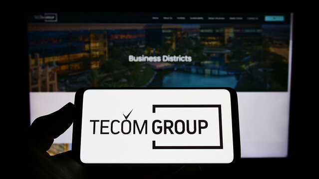 Stuttgart, Germany - 06-25-2022: Person holding smartphone with logo of Emirati real estate company Tecom Group LLC on screen in front of website. Focus on phone display.