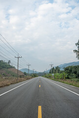 Fototapeta na wymiar Paved road Thailand.The asphalt road on both sides of the road is covered with grass.