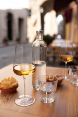 White wine and water outdoors in an mediterranean old town. Vertical holiday background with short depth of field.