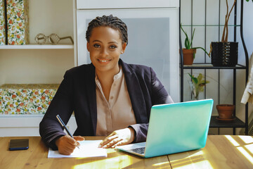 Young adult black executive businesswoman signing contract for client smiling looking at camera in...