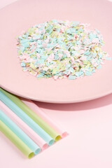 Drinking straws and plate full of microplastics on a pink background. Impact of micro plastic on the food chain. The idea of micro plastic pollution. Concept of environmental damage