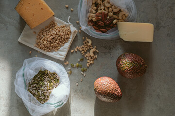 Fresh avocados, cheese and butternut in eco bags on table in the kitchen. Zero waste shopping concept. Healthy fats.