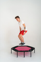 Obraz premium Strong fitness man In sportswear jumping on sport trampoline