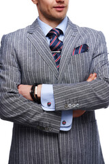 Cropped close-up shot of a man in a gray pinstripe suit, a blue shirt with a blue tie with red...