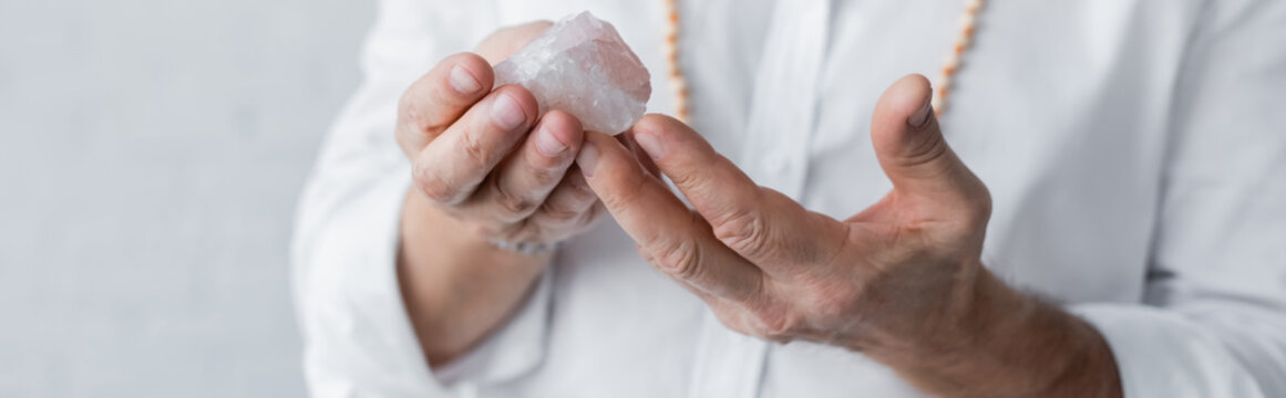cropped view of guru master holding selenite crystal isolated on grey, banner.
