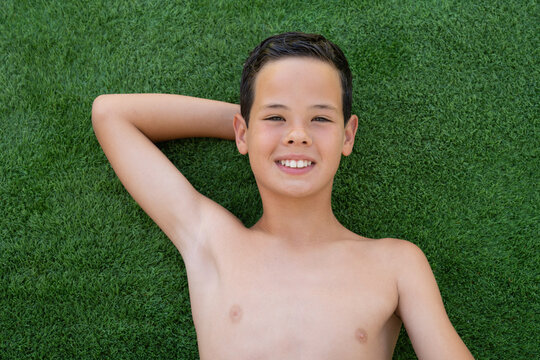 Portrait Of Beautiful Smiling Boy Lying On The Grass From Above