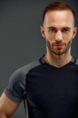 Fototapeta premium Croped portrait of male fitness model in black top relaxing after workout. Grey background with room for text, Copy space.