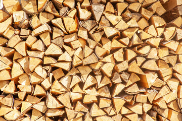 Textured firewood background of chopped wood for kindling and heating the house, a woodpile with stacked firewood. Concept of economic fuel crisis.