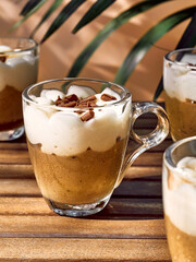 Traditional Italian dessert Tiramisu in glass cups on wooden table. National cuisine recipe. Summer refresh coffee cream sweet mousse dish.