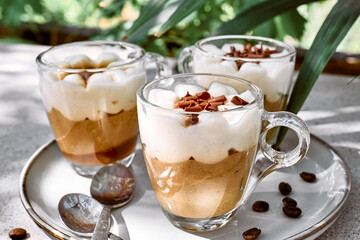 Traditional Italian dessert Tiramisu in glass cups on gray table. National cuisine recipe. Summer refresh coffee cream sweet mousse dish.