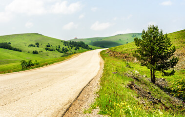 Fototapeta na wymiar Empty asphalt mountain road between green hills and meadows 