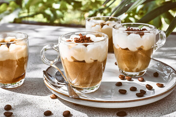 Traditional Italian dessert Tiramisu in glass cups on gray table. National cuisine recipe. Summer refresh coffee cream sweet mousse dish.