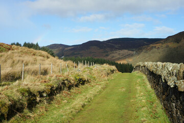 Landscapes of Ireland.A path in a mountain valley running along an old stone wall.