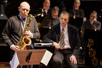 Big Band: Jazz Sax Solo. A saxophonist solos while the band listens in the background. From an image series of musicians in a swing Jazz band.