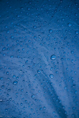 Rainwater drops on a blue background made of waterproof fabric. Texture and abstract background.