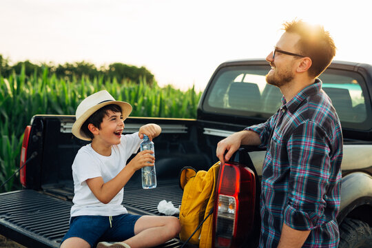 father and son together on corn field. examine crop. drinking water from bottle