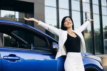 Happy business woman standing by her car