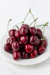 A mound of cherries on a white plate. Appetizing berries on a white background. Vitamins and a healthy lifestyle