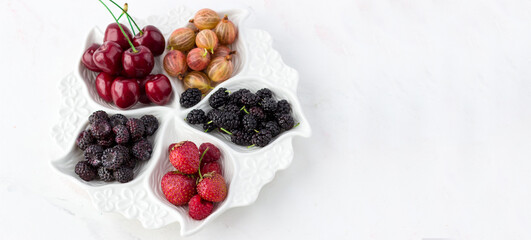 Berry plate on a white background. Strawberries, gooseberries, cherries, raspberries and mulberries