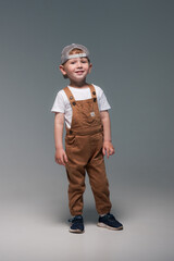 boy in a cap in overalls and a white t-shirt