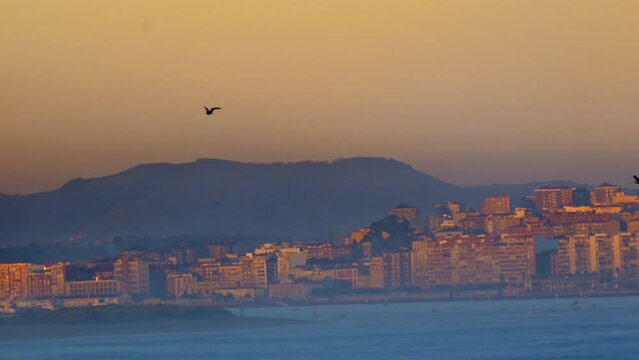 amazing shoot lateral panning from Somo beach where we see the bay of Santander during sunrise with its orange and purple colors and the buildings of Santander with a wonderful and unique light.