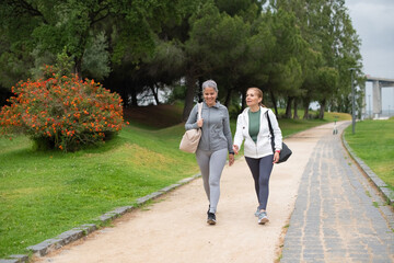 Satisfied senior friends talking in park. Women in sportive clothes communicating on cloudy day. Sport, friendship concept © KAMPUS