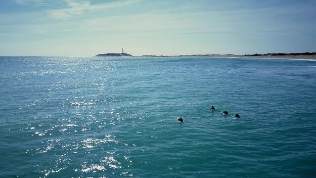amazing drone shoot over Ca&ntilde;os de Meca beach in Cadiz ,Spain where the drone glides  to the beach and shows us the sea with some surfers, the waves and the lighthouse during a sunny summer day
