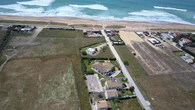 amazing drone shoot over Palmar beach in Cadiz Spain where the drone glides from the small country houses to the beach and shows us the sand and the sea with the waves during a sunny summer day