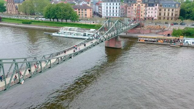 People Walking At Iron Footbridge Spanning The River Main In Frankfurt, Germany. - aerial
