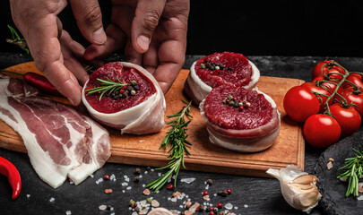 male hands holding beef meat on a dark background, Whole piece of tenderloin with steaks and spices ready to cook, Long banner format