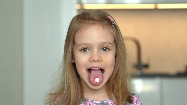 Happy little child eats pill and fun stick out tongue with vitamin. Medicines, medicament and drug. Health, care and treatment for children.