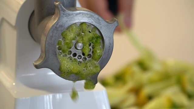 Close up of meat grinder grinds fresh bell pepper in kitchen. Lecho. Preparation of pickles, canned vegetables