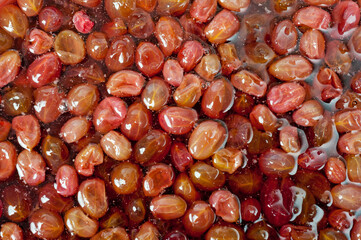 Close-up shot of red ripe gooseberry jam in sweet syrup.
