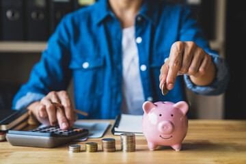 woman holds a coin in a pig-shaped piggy bank to save money for the future. after retirement and...