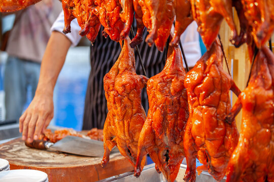 An Asian chef cater cutting Chinese style roasted duck dish menu for guests in Chinese ceremony party festival or catering in wedding outdoor event at hotel yard garden. International Food Concept