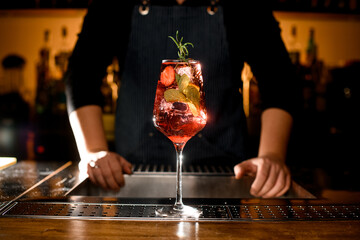 glass with cold drink with strawberries and mint decorated with branch of rosemary on bar