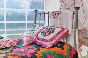 Traditional decor of bed in Tatar vintage style. Woven bedspread, pillows embroidered with ribbons