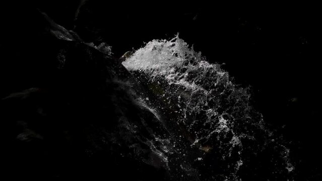 Splashing water of a waterfall in the black background 