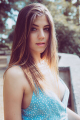 Naklejka premium Portrait of a beautiful young girl. Long brown hair. Big eyes and intense gaze. Outdoors, daylight.