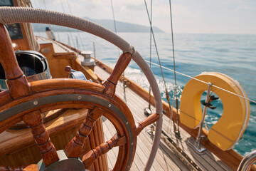 Closeup of wooden steering wheel on empty boat sailing the ocean. Closeup of empty boat deck with...