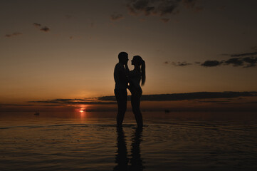Fototapeta na wymiar Romantic couple on the background of sunset near the ocean. Sunset walk along the ocean