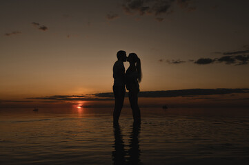 Romantic couple on the background of sunset near the ocean. Sunset walk along the ocean