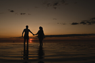 Fototapeta premium Romantic couple on the background of sunset near the ocean. Sunset walk along the ocean