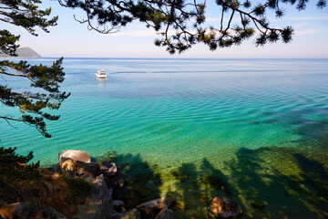 Yacht in a bay with turquoise water color. Picturesque seascape. Coniferous forest. Untouched nature, rest in a wild place.