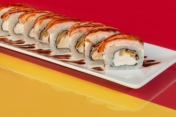 Nigiri sushi sets, Uramaki, California, Philadelphia, on a white plate. Near ginger and wasabi. Soy sauce in a white bowl. On a colored background.